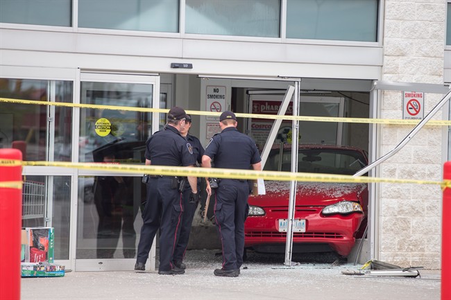 Police investigate after a car backed through the entrance of Costco in London, Ont., on Friday, July 25, 2014. Six people were injured, including a child who was in critical condition, after a car crashed through the front doors of a busy Costco store. THE CANADIAN PRESS/ Geoff Robins.