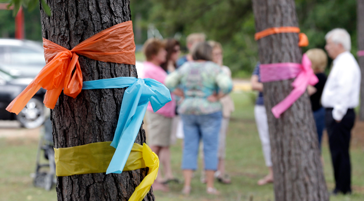 Faculty and parents gather outside Lemm Elementary School after placing ribbons on the trees in honor of those killed in a multiple shooting Thursday, July 10, 2014, in Spring, Texas. 
