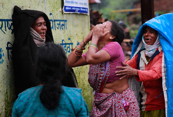 Relatives wail after seeing the body of a victim after a massive landslide in Malin village in Pune district of western Maharashtra state, India, Thursday, July 31, 2014.