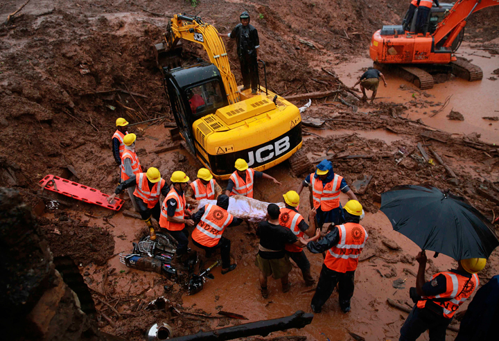 Rescue workers carry the body of a victim after a massive landslide in Malin village in Pune district of western Maharashtra state, India, Thursday, July 31, 2014.