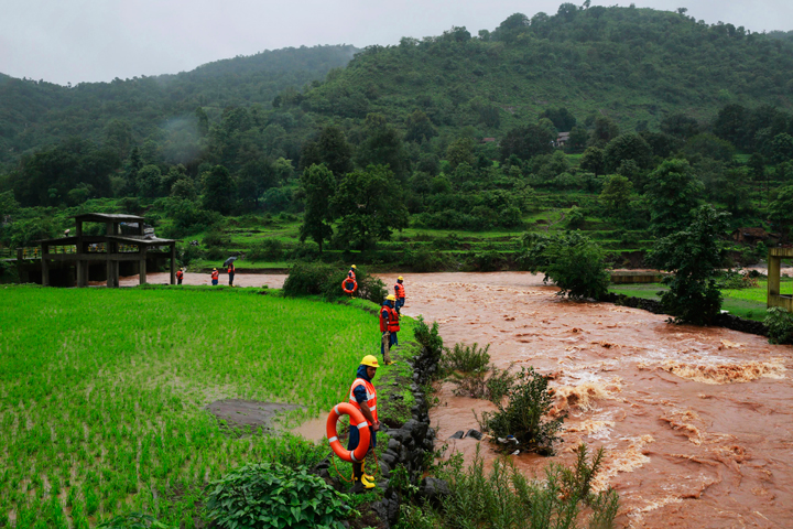 Rescue workers stand on the bank of a river after a massive landslide in Malin village in Pune district of western Maharashtra state, India, Thursday, July 31, 2014.