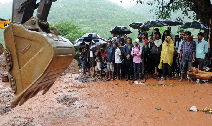 Villagers look on as rescue work continues at the scene of the landslide in Malin village in Pune district of India’s western state of Maharashtra on July 31, 2014.