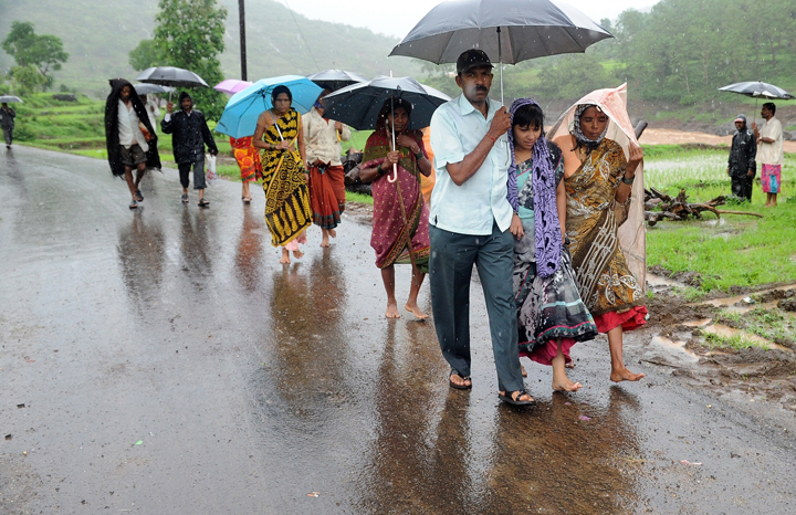 A mother (2nd R) who had lost her three children in a landslide, is accompanied by villagers to a temporary mortuary at Malin village in Pune district of India’s western state of Maharashtra on July 31, 2014.