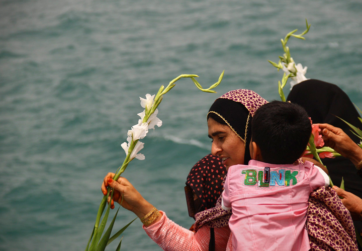 In this FILE photo, an Iranian woman scatters flower into the Persian Gulf waters, on Sunday, July 3, 2011. Iranians were mourning an airline tragedy tossed flowers in the Gulf on Sunday at the site where an Iranian passenger plane was downed by a U.S. warship, killing all 290 aboard in an incident Washington describes as a mistake but many in Iran consider a deliberate attack. More than 80 relatives of those killed in the July 3, 1988 downing of the Iran Air A300 dropped red, white and pink flowers into the sea. More flowers cascaded down from helicopters.