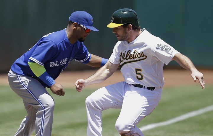 Oakland Athletics' John Jaso, right, beats the tag of Toronto Blue Jays third baseman Juan Francisco as he advances to third base on a sacrifice fly by Alberto Callaspo in the first inning of a baseball game Sunday, July 6, 2014, in Oakland, Calif.