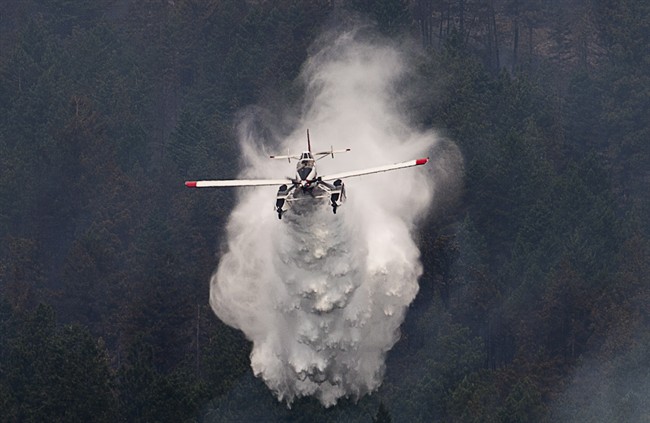 A water bomber drops water on a hillside in West Kelowna, B.C. Friday, July, 18, 2014. Over 2500 residents of the area were evacuated when the fire suddenly grew in size threatening nearby homes. THE CANADIAN PRESS/Jonathan Hayward.