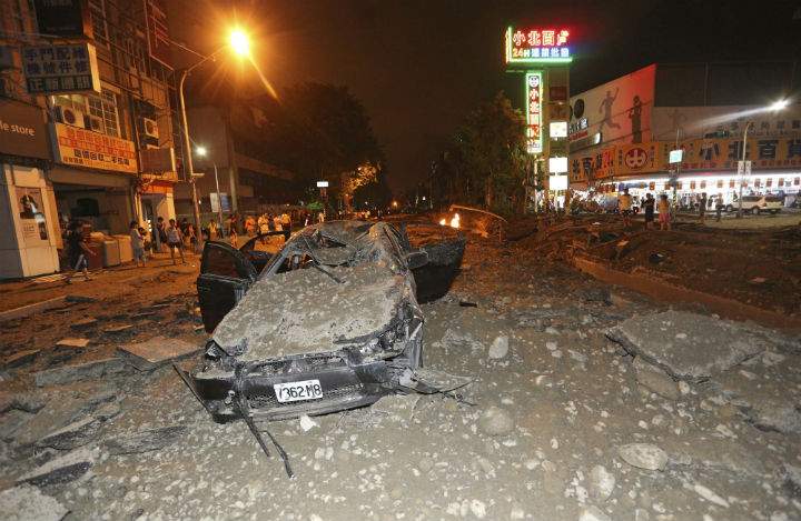 A crushed vehicle sits in rubble on a destroyed street after multiple explosions from an underground gas leak in Kaohsiung, Taiwan, early Friday, Aug. 1, 2014. A massive gas leakage early Friday caused five explosions that killed several people and injured over 200 in the southern Taiwan port city of Kaohsiung.