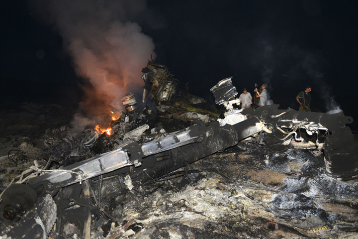 People stand on July 17, 2014, amongst the wreckage of the Malaysian airliner carrying 298 people from Amsterdam to Kuala Lumpur after it crashed, near the town of Shaktarsk, in rebel-held east Ukraine. Alexander Khudoteply/AFP/Getty Images