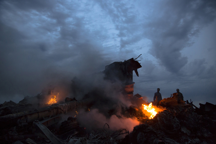 People walk amongst the debris at the crash site of a passenger plane near the village of Grabovo, Ukraine, Thursday, July 17, 2014. AP Photo/Dmitry Lovetsky