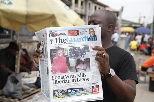 A man reads a newspaper on a Lagos street with the headline Ebola Virus kills Liberian in Lagos, Saturday, July 26, 2014. 