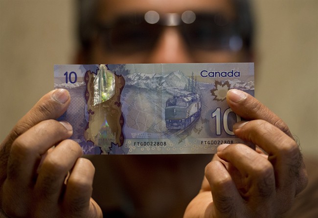 Ryerson University professor Hitesh Doshi poses with a $10 Canadian bank note in Mississauga, Ont. on Monday, July 28, 2014. Doshi discovered an error in a mountain which adorns one of Canada's new plastic bank notes. THE CANADIAN PRESS/Nathan Denette.