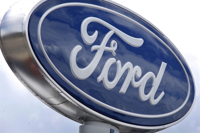 In this photo made on Thursday, June 5, 2014, clouds are reflected in the Ford sign at a dealership in Wexford, Pa. 