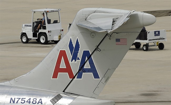 In this May 15, 2014 photo, a ramp worker rolls past an American Airlines McDonnell Douglas MD-82 at the Tampa International Airport in Tampa , Fla.