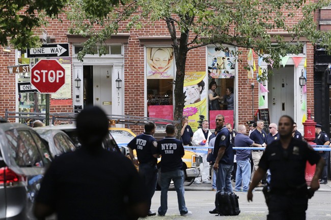 Police officers stand guard at the scene of a shooting, Monday, July 28, 2014, in the Greenwich Village neighborhood in New York. Authorities said a sex-assault suspect got in a shootout with law enforcement in New York City that left the suspect dead and two federal marshals and a police officer wounded. (AP Photo/Mark Lennihan).