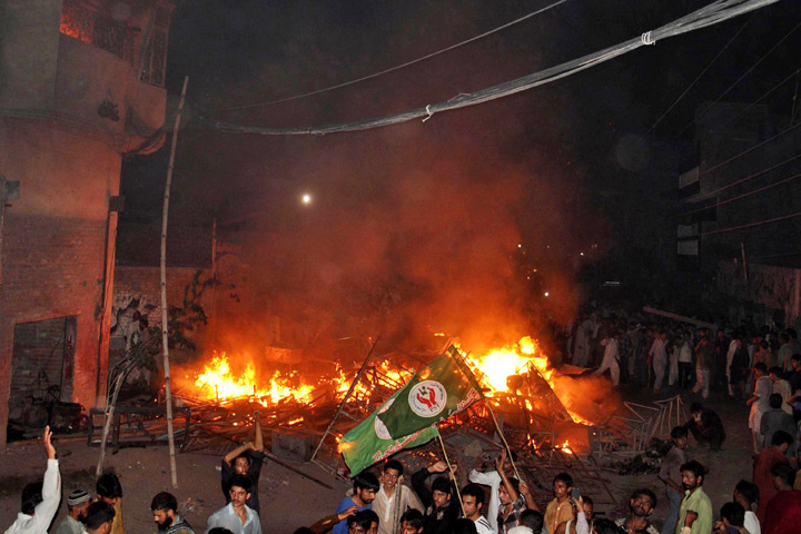 This photograph taken on July 27, 2014 shows an angry mob after they set fire to household items belonging to a minority Ahmadi Muslim resident in the low-income Arafat Colony of the eastern city of Gujranwala, some 112 kilometres north of Lahore. An angry mob in Pakistan torched an Ahmadi Muslim minority neighbourhood killing a woman and two girls in a row over blasphemy, police said, in the latest attack on one of the country's most persecuted groups. 