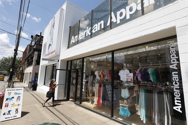 A woman walks past a sandwich-board sign advertising dog fashions into the American Apparel store in the Shadyside neighborhood of Pittsburgh on Wednesday, July 9, 2014. 