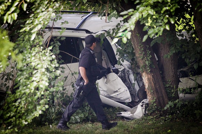 A police officer walks past the wreckage of a carjacked vehicle that police say hit a group of people on a corner in Philadelphia on Friday, July 25, 2014, killing two children and critically injuring three other people. (AP Photo/Philadelphia Daily News, Alejandro A. Alvarez).