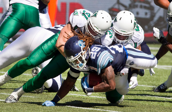 Toronto Argonauts Brandon Underwood dives forward for a first down under the tackles of Saskatchewan Roughriders Sam Hurl and Paul Woldu during first half action in their CFL game in Toronto Saturday July 5, 2014.