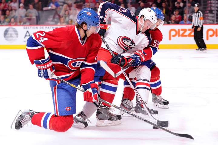 Sean Collins #43 of the Columbus Blue Jackets attempts to move the puck past Francis Bouillon #55 and Jarred Tinordi #24 of the Montreal Canadiens during the NHL game at the Bell Centre on October 17, 2013 in Montreal, Quebec, Canada.