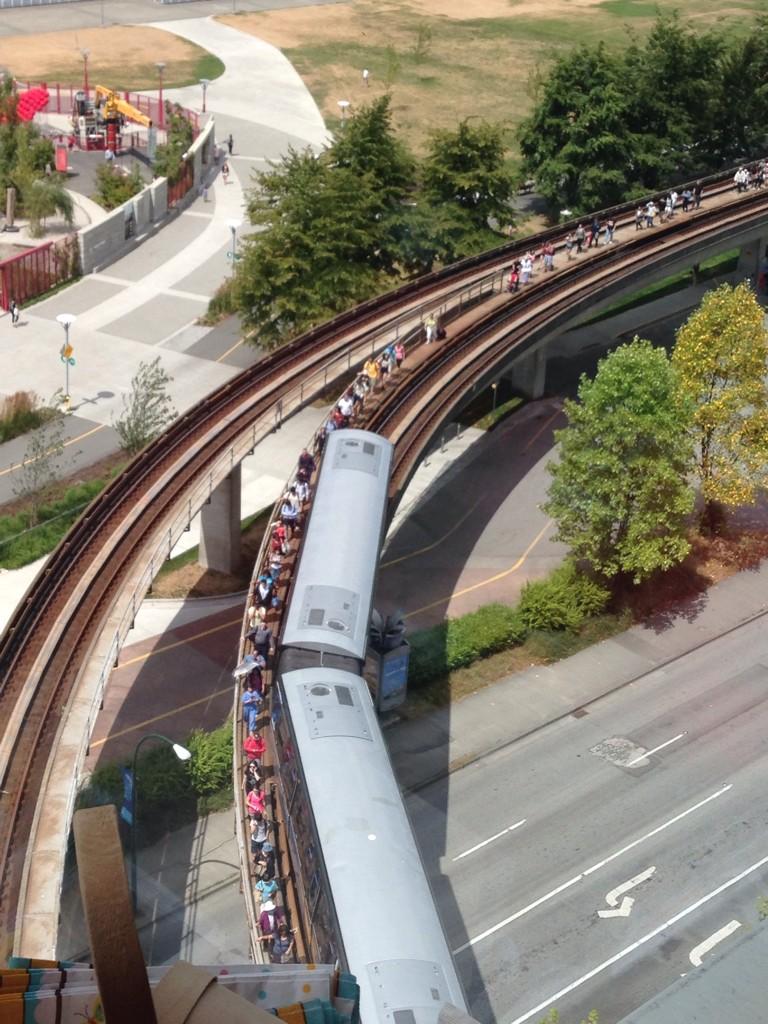 People walking on the tracks leaving the SkyTrain at Main Street station.