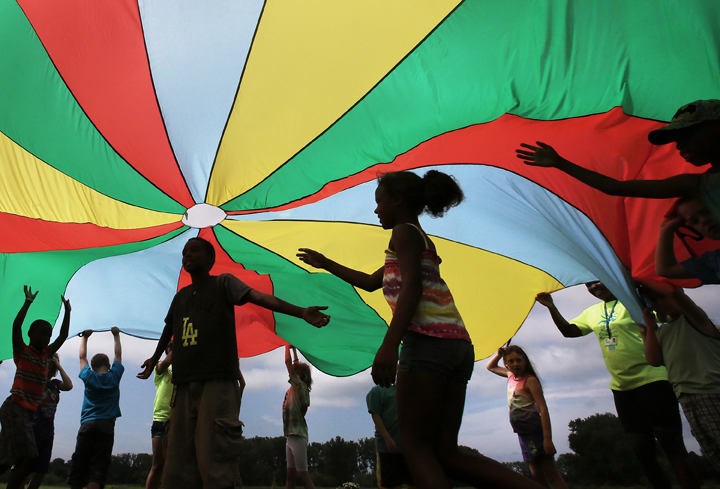 FILE PHOTO: Elementary school students enrolled in a summer camp program play under a colorful canopy.