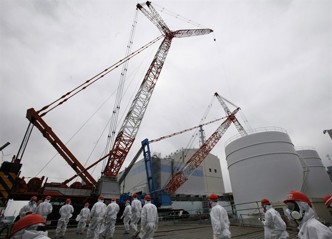 Tokyo Electric Power Co. (TEPCO) staff and journalists walk in front of the No. 1 reactor at the Fukushima Dai-ichi nuclear power plant during a press tour in Okuma town, Fukushima prefecture, northeastern Japan in March 2014.