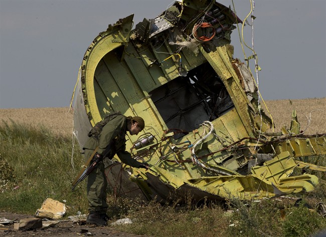 FILE - In this July 22, 2014 file photo, a pro-Russian rebel touches the MH17 wreckage at the crash site of Malaysia Airlines Flight 17, near the village of Hrabove, eastern Ukraine. 