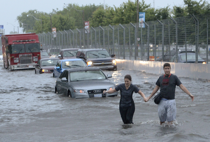 People wade through flood water on Lakeshore West during a storm in Toronto on Monday, July 8, 2013. 