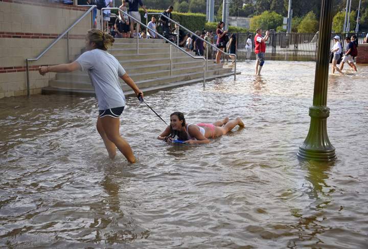 A woman pulls another on a body board through water on the quad of UCLA after flooding from a broken 30-inch water main under nearby Sunset Boulevard inundated a large area of the campus in the Westwood section of Los Angeles, Tuesday, July 29, 2014. AP Photo/Mike Meadows