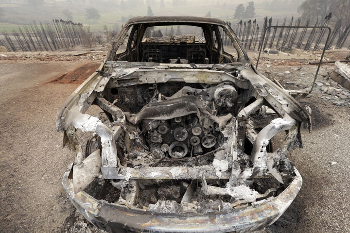 he shell of a burned-out car remains from a wildfire the night before, Friday, July 18, 2014, in Pateros, Wash.
