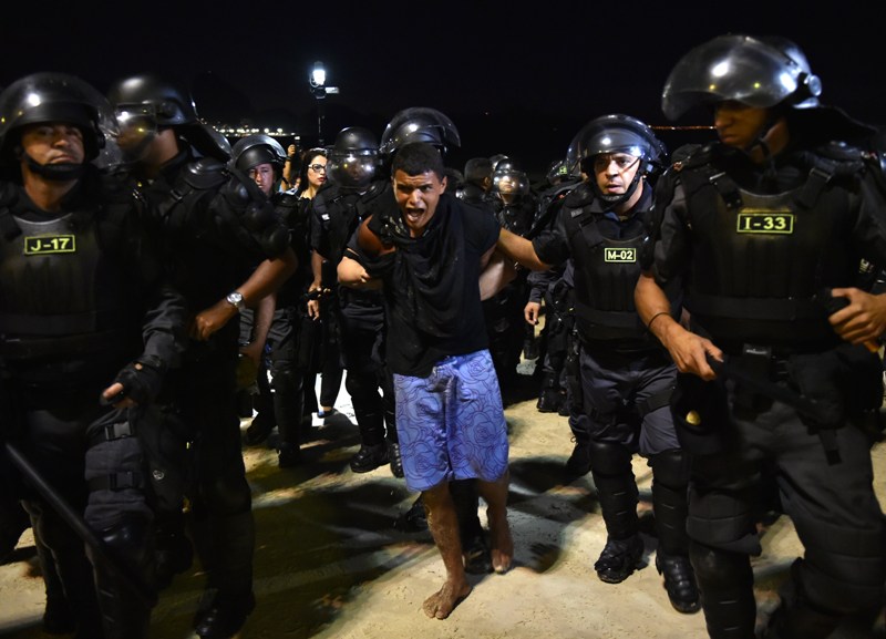 Riot police arrest a protester in the vicinity of the FIFA Fan Fest in Copacabana Beach in Rio de Janeiro, Brazil on June 12, 2014. . AFP PHOTO / YASUYOSHI CHIBA .