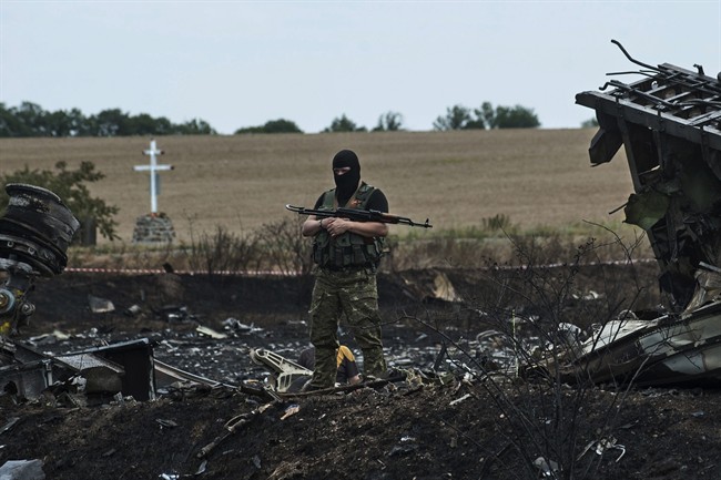 A pro-Russian fighter guards the crash site of Malaysia Airlines Flight 17 near the village of Hrabove, eastern Ukraine, Sunday, July 20, 2014.