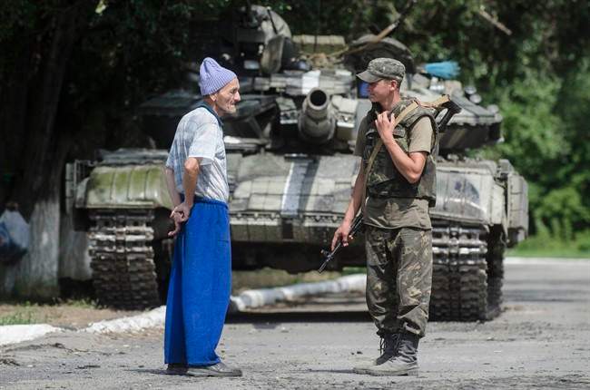A local citizen speaks to a Ukrainian government soldier guarding a checkpoint outside the city of Siversk, Donetsk region, eastern Ukraine, Saturday, July 12, 2014. 