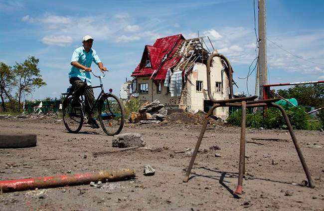 A man rides a bike past a house damaged during fighting, outside the city of Slovyansk, Donetsk Region, eastern Ukraine Thursday, July 10, 2014. In the past two weeks, Ukrainian government troops have halved the amount of territory held by the rebels. Now they are vowing a blockade of Donetsk. In another sign of deteriorating morale among rebels, several dozen militia fighters in Donetsk abandoned their weapons and fatigues Thursday, telling their superiors they were returning home. 