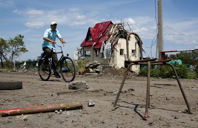 A man rides a bike past a house damaged during fighting, outside the city of Slovyansk, Donetsk Region, eastern Ukraine Thursday, July 10, 2014. In the past two weeks, Ukrainian government troops have halved the amount of territory held by the rebels. Now they are vowing a blockade of Donetsk. In another sign of deteriorating morale among rebels, several dozen militia fighters in Donetsk abandoned their weapons and fatigues Thursday, telling their superiors they were returning home. 