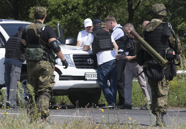 Members of the OSCE mission to Ukraine examine a map as they try to estimate security conditions outside the city of Donetsk, eastern Ukraine Wednesday, July 30, 2014. (AP Photo/Dmitry Lovetsky).