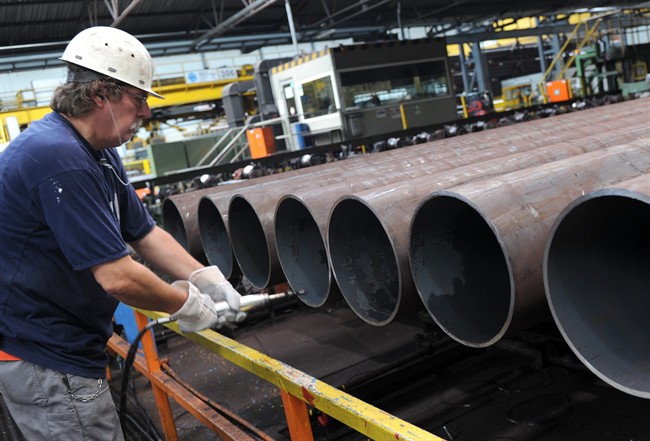An employee checks a steel pipe in the manufacturing hall. 