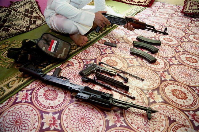 An Iraq weapon dealer cleans his weapon at his home in Baghdad, Iraq, Saturday, July 12, 2014. The weapon dealer said prices of weapons and ammunition have nearly doubled in recent weeks in Iraq. (AP Photo/Karim Kadim).