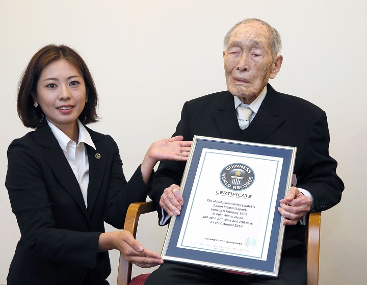 Sakari Momoi, a retired Japanese educator, poses for a photo after receiving a certificate from a Guinness World Records official, left, in Tokyo Wednesday, Aug. 20, 2014.