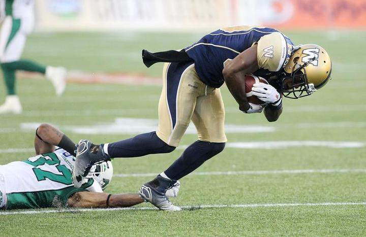 Clarence Denmark #89 of the Winnipeg Blue Bombers breaks free from the grasp of Rod Williams #37 of the Saskatchewan Roughriders on Thursday in Winnipeg.