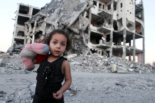 A Palestinian girl is among the remains of buildings destroyed by Israeli army as Palestinians get back to Beit Lahia to inspect their houses and collect their leftover belongings during a 72-hour humanitarian ceasefire in Gaza on August 12, 2014. (Photo by Naaman Omar/Anadolu Agency/Getty Images).