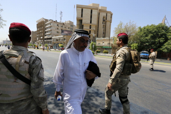 An Iraqi man walks past security forces in Baghdad's Firdos Square as he arrives for a rally to show his support for Prime Minister Nuri al-Maliki on August 13, 2014. Iraq's premier designate Haidar al-Abadi is gaining widespread support from countries hoping political reconciliation will undercut jihadists, as Iran further undercut Nuri al-Maliki's bid to cling to power.