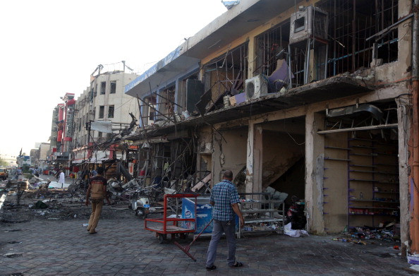 Iraqis walks past debris in the aftermath of an explosion in Baghdad's commercial district of New Baghdad on August 14, 2014. 