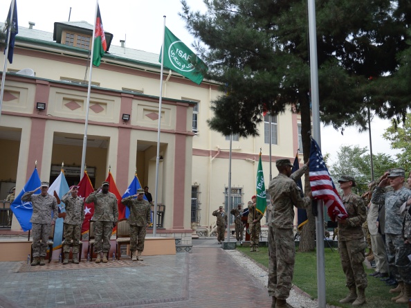 US soldiers raise a flag as outgoing International Security Assistance Force (ISAF) commander US General Joseph Dunford (L) and incoming US Army General James Campbell (R) salute during a change of command ceremony at the ISAF headquarters in Kabul on August 26, 2014.  