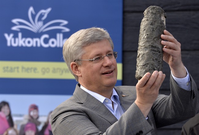 Prime Minister Stephen Harper holds up a permafrost core sample as he takes part in an event at the Yukon college in Whitehorse, Thursday August 21, 2014. 