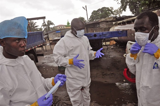 Liberian health worker prepare their Ebola protective gear before removing the body of a man that they believe died from the Ebola virus in Monrovia, Liberia, Friday, Aug. 29, 2014. 
