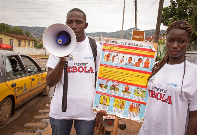 A man and woman taking part in a Ebola prevention campaign holds a placard with an Ebola prevention information message in the city of Freetown, Sierra Leone, Wednesday, Aug. 6, 2014.