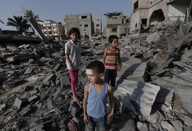 Palestinian Seraj Ismail Abdel Al, 5, lightly wounded in an overnight Israeli strike, inspects the damage to several buildings in Gaza City, northern Gaza Strip, Saturday, Aug. 2, 2014. (AP Photo/Lefteris Pitarakis).