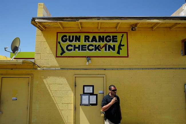 An employee smokes outside of an office for the Last Stop outdoor shooting range Wednesday, Aug. 27, 2014, in White Hills, Ariz. Instructor Charles Vacca was accidentally killed at the range by a 9-year-old with an Uzi submachine gun. 