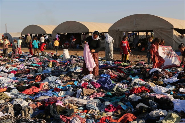 Displaced Iraqis from the Yazidi community look for clothes to wear among items provided by a charity organization at the Nowruz camp, in Derike, Syria, Tuesday, Aug. 12, 2014. In the camps here, Iraqi refugees have new heroes: Syrian Kurdish fighters who battled militants to carve an escape route to tens of thousands trapped on a mountaintop. While the U.S. and Iraqi militaries dropped food and water to the starving members of Iraq’s Yazidi minority, the Kurds took it on themselves to rescue them, a sign of how Syria’s Kurds, like Iraq’s, are using the region’s conflicts to establish their own rule. 